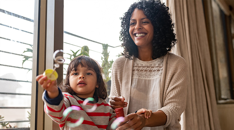 Little girl and her mother playing with a bubble wand