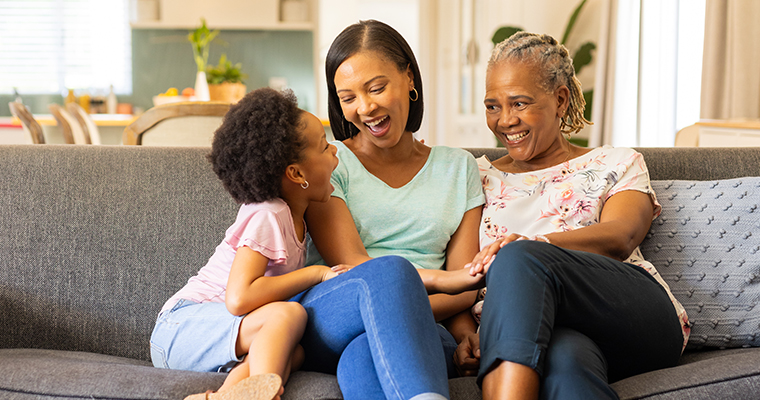 Three generations sitting on a couch laughing